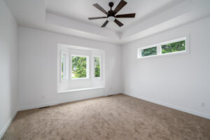 white room with ceiling fan and bay window